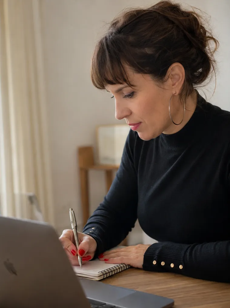 Cinzia Ruggeri writing at a table beside her laptop